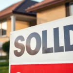 Bright sold sign being held by a realtor, prominently displaying "Sold" in bold letters for eye-catching real estate marketing.